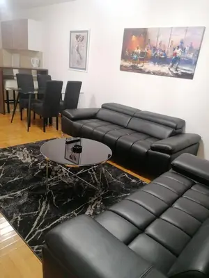 a living room with black leather couches and a table at Apartman Casa Banja Luka in Banja Luka