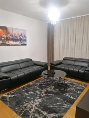 a living room with black leather couches and a table at Apartman Casa Banja Luka in Banja Luka