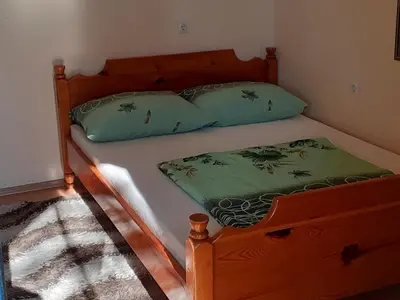 a wooden bed with two green pillows on it at Smještaj na selu,porodica Gvozdenac in Šipovo