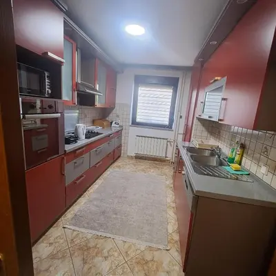 a kitchen with red cabinets and a sink and a counter at Villa Behić in Bihać