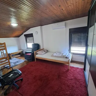 a room with a bed and a chair and a red rug at Villa Behić in Bihać