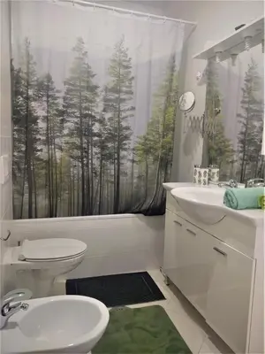 a bathroom with a toilet and a shower curtain with trees at Best Location - Heart Of Tuzla in Tuzla