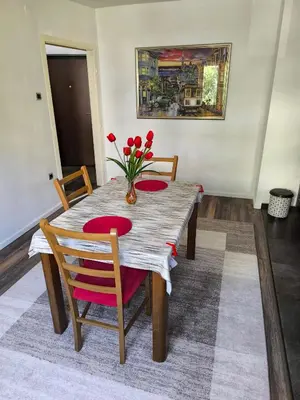 a dining room table with red chairs and a vase of flowers at Apartman Banja Luka 2 in Banja Luka