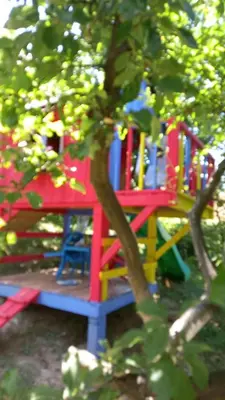 a colorful play structure sitting behind a tree at Medena oaza mira in Visoko