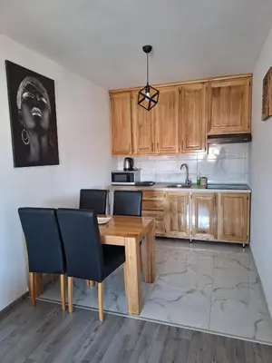 a kitchen with wooden cabinets and a wooden table and chairs at Apartman Lilly in Modriča