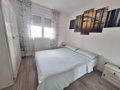 a white bedroom with a bed and a window at Apartman Lilly in Modriča