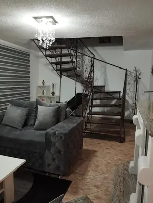 a living room with a couch and a spiral staircase at City villa Bihac in Bihać
