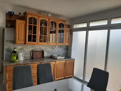 a kitchen with wooden cabinets and a table with chairs at City villa Bihac in Bihać