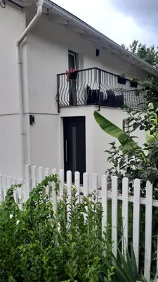 a white house with a white fence and a balcony at Ravne Rest House in Visoko