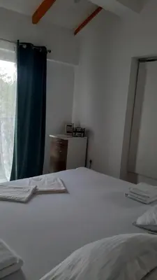a bedroom with a white bed with a blue curtain at Ravne Rest House in Visoko