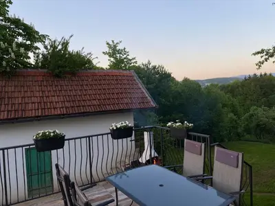 a table and chairs on a balcony with a view of a house at Ravne Rest House in Visoko