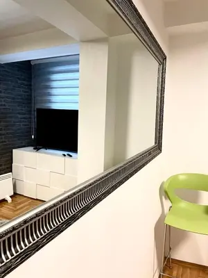 a mirror in a living room with a green chair at Apartman CITY CENTER 3-šetalište in Prijedor