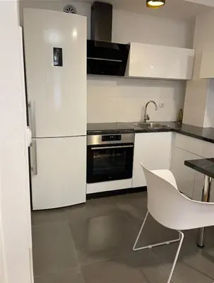 a kitchen with a white refrigerator and a white chair at Apartman CITY CENTER 3-šetalište in Prijedor