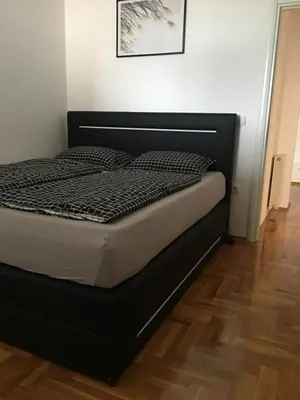 a bed with a black bed frame in a room at Apartman CITY CENTER 3-šetalište in Prijedor