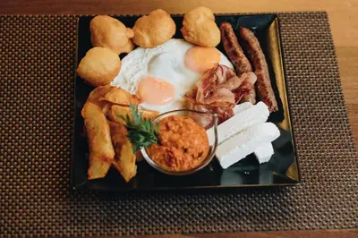 a plate of breakfast food with fried eggs and dips at Ribarski konaci in Doboj