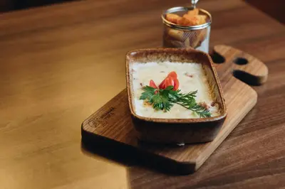 a bowl of soup on a wooden plate on a table at Ribarski konaci in Doboj