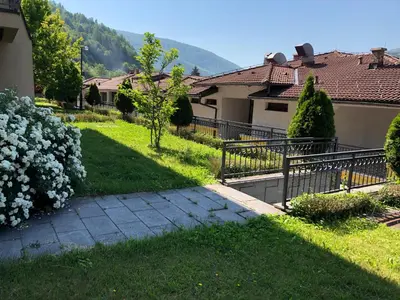 a house with a walkway in a yard with flowers at Sound apartment in Fojnica