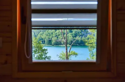 a window with a view of a lake with a tree at Malena Plivsko Jezero Jajce in Jajce