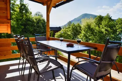 a table and chairs on a porch with wine glasses at Malena Plivsko Jezero Jajce in Jajce