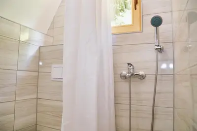 a shower with a shower head and a shower curtain at Malena Plivsko Jezero Jajce in Jajce