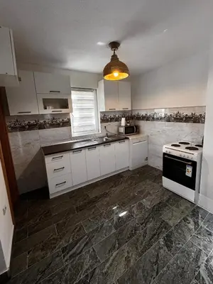 a kitchen with white cabinets and a black stove at Kuća za odmor Aiman in Mahala