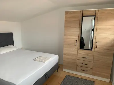 a bedroom with a white bed and a wooden cabinet at Nisa & De Apartmani in Bihać