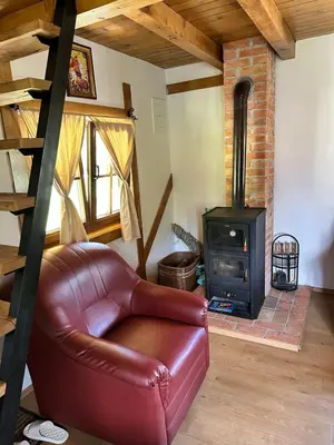 a living room with a leather couch and a wood stove at Vikendica na Janju in Šipovo