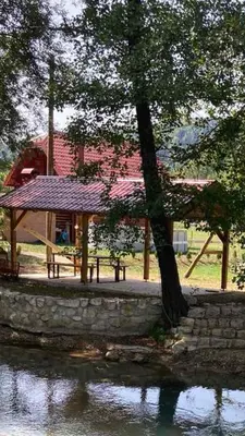 a pavilion with a tree next to a body of water at Vikendica na Janju in Šipovo