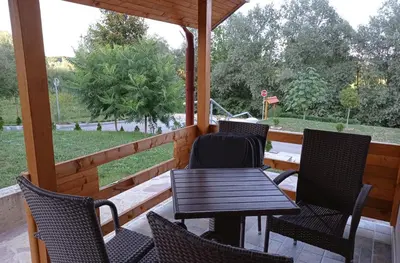 a porch with a table and chairs and a view of a park at Sherwood resort in Bihać