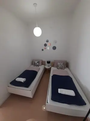 a bedroom with two beds and a white wall at King's Cave in Jajce