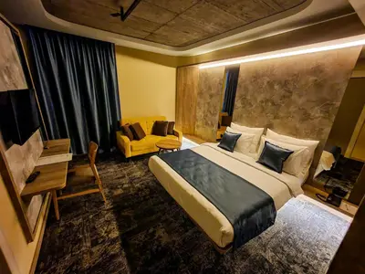 a bedroom with a large bed and a yellow couch at Hotel City Code in Zenica
