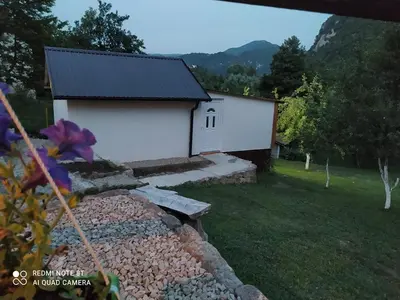 a white building with a stone wall in front of it at Lenilenii Bungalows in Jajce