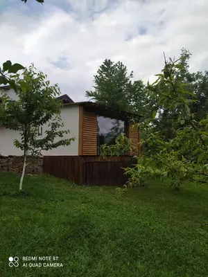 a small house in a yard with trees at Lenilenii Bungalows in Jajce