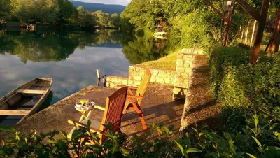 a couple of chairs sitting on a table next to a lake at Una Verde in Bihać