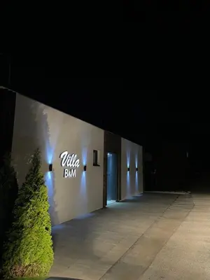 a building with a sign on the side of it at night at Apartments B&M in Visoko