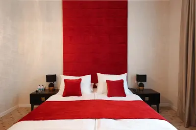 a bedroom with a red headboard and a bed with red pillows at Hotel Vidović in Banja Luka