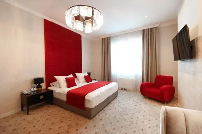a bedroom with a large bed and a red headboard at Hotel Vidović in Banja Luka