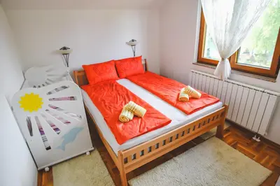 a bedroom with a large bed with red sheets and gold pillows at Aventurin Superior Apartments in Bihać