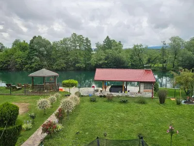 a small house with a red roof next to a lake at Aventurin Superior Apartments in Bihać