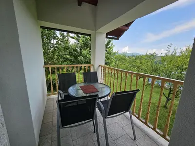 a porch with a table and chairs on a balcony at Guest house Al Meri in Travnik