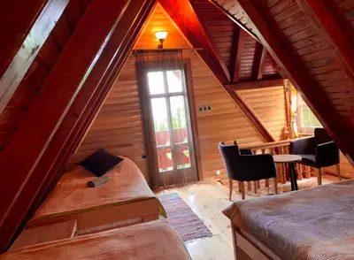 a attic room with a bed and a table and chairs at Planinska kuca za odmor-Mlinista in Landeke