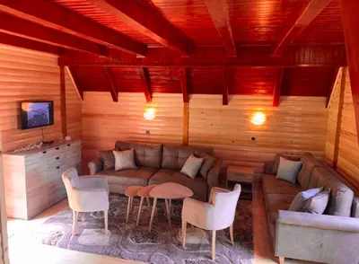 a living room with a couch and a table and chairs at Planinska kuca za odmor-Mlinista in Landeke