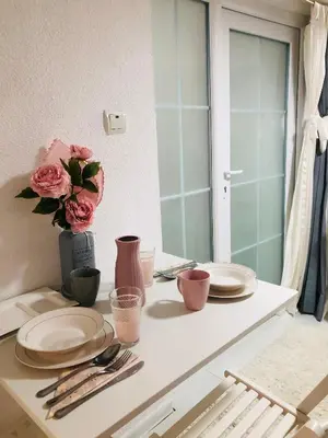 a table with plates and a vase with pink roses at Apartman Indira in Visoko