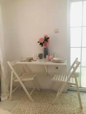 a white table with a vase of flowers and a chair at Apartman Indira in Visoko