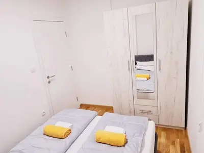 a bedroom with two beds with yellow pillows and a cabinet at Apartman Mirabell, Doboj in Doboj