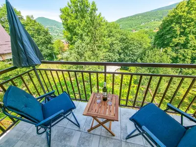 a balcony with two chairs and a table and an umbrella at Aparthouse Bilic in Jajce