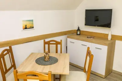 a dining room with a table and chairs and a tv at Aparthouse Bilic in Jajce