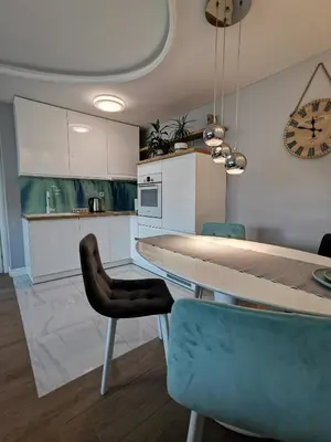 a kitchen with a table and chairs and a clock at Lux Apartment with Sauna & Balcony in Banja Luka