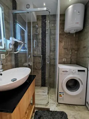 a bathroom with a sink and a washing machine at Lux Apartment with Sauna & Balcony in Banja Luka