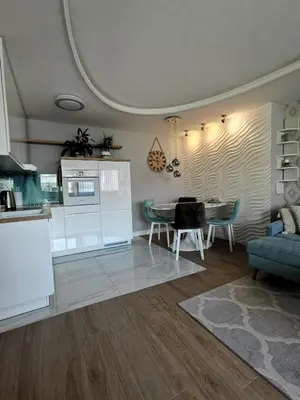 a living room with a table and a kitchen at Lux Apartment with Sauna & Balcony in Banja Luka